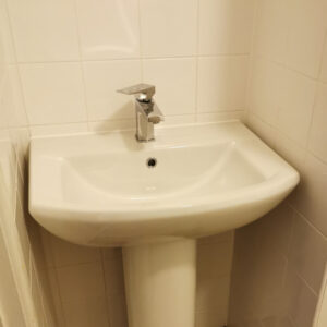 White sink with tap against white tiled wall